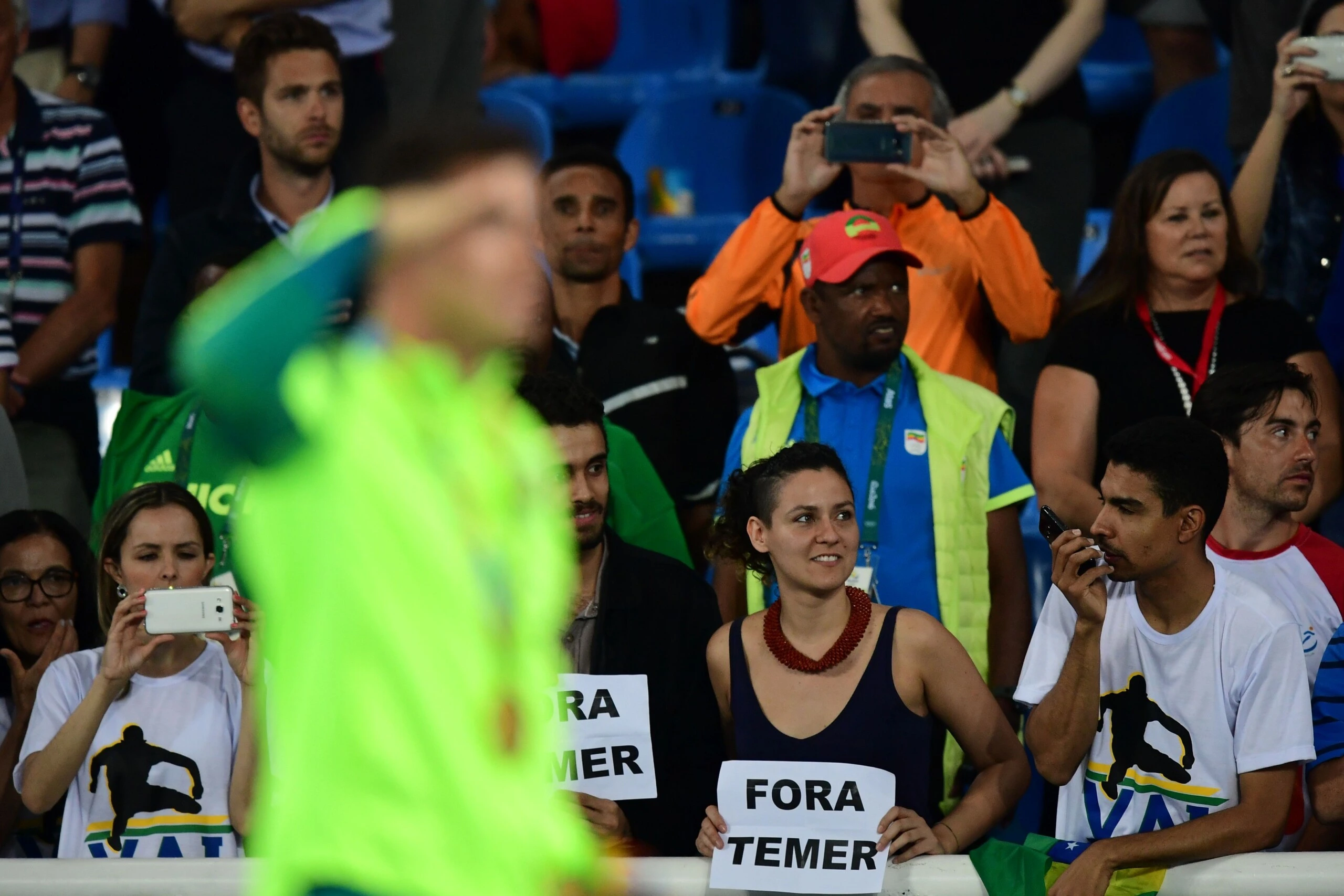 Gold medallist Brazil's Thiago Braz Da Silva (L) celebrates on the podium as people hold a banner reading "out with Temer" (Brazil's interim president Michel Temer) at the medal ceremony for the men's pole vault during the athletics event at the Rio 2016 Olympic Games at the Olympic Stadium in Rio de Janeiro on August 16, 2016. / AFP / FRANCK FIFE (Photo credit should read FRANCK FIFE/AFP/Getty Images)