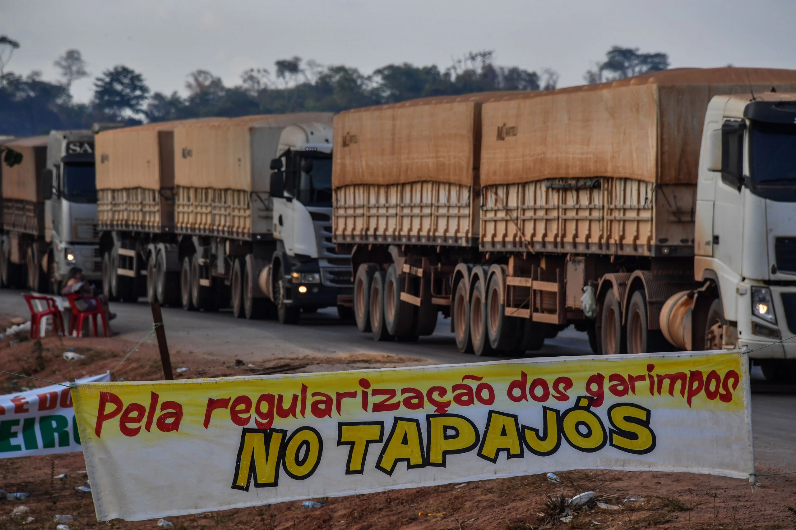 Truckers line up behind a banner reading "For the regularization of garimpos (illegal mines) in Tapajos", referring to the Tapajos River, on the BR 163 highway, blocked by "garimpeiros" -illegal gold miners- during a protest in Morais Almeida, Itaituba, Para state, Brazil, on September 13, 2019. - Members of an indigenous tribe in the Amazon in northern Brazil on Friday called for wildcat miners to be allowed to prospect for gold on their land, saying it was a source of income. (Photo by NELSON ALMEIDA / AFP) (Photo credit should read NELSON ALMEIDA/AFP/Getty Images)