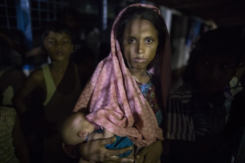 KUTUPALONG, BANGLADESH - SEPTEMBER 29: Hasina Begum, age 18, holds her newborn baby, 8 days old, born while she was walking in the forest escaping from Myanmar September 29, 2017 in Kutupalong , Bangladesh. She is now living inside a makeshift shelter packed with new arrivals. Over a half a million Rohingya refugees have fled into Bangladesh from the horrific violence in Rakhine state in Myanmar causing a humanitarian crisis. (Photo by Paula Bronstein/Getty Images)