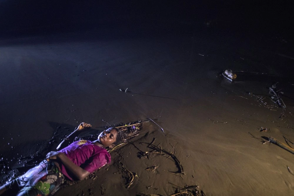 PATUWARTEK, INANI BEACH, BANGLADESH - SEPTEMBER 28: (EDITORS NOTE: Image depicts death.) The body of a Rohingya woman lays on a beach washed up after a boat sunk in rough seas off the coast of Bangladesh carrying over 100 people September 28 close to Patuwartek, Inani beach, Bangladesh. Seventeen survivors were found along with the bodies of 15 women and children. Over 500 Rohingya refugees have fled into Bangladesh since late August during the outbreak of violence in Rakhine state as Myanmar's de facto leader Aung San Suu Kyi downplayed the crisis during a speech in Myanmar this week faces and defended the security forces while criticism on her handling of the Rohingya crisis grows. Bangladesh's prime minister, Sheikh Hasina, spoke at the United Nations General Assembly last week, focusing on the humanitarian challenges of hosting the minority Muslim group who currently lack food, medical services, and toilets, while new satellite images from Myanmar's Rakhine state continue to show smoke rising from Rohingya villages. (Photo by Paula Bronstein/Getty Images)
