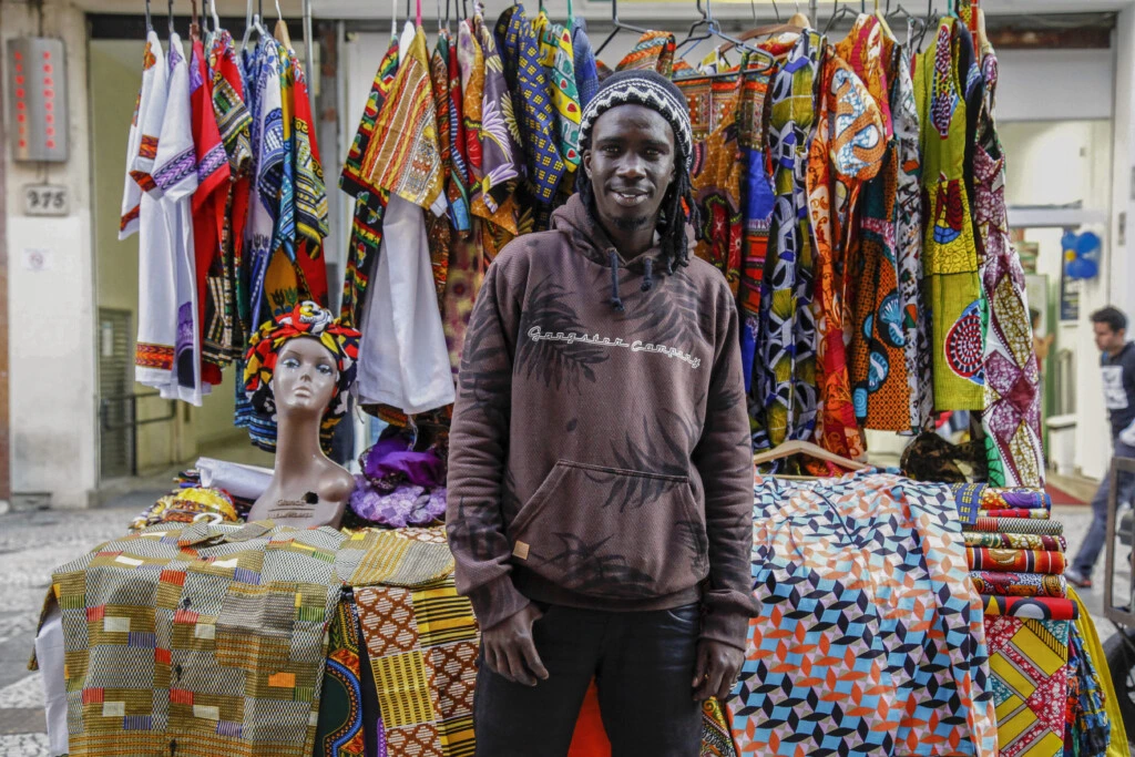 O refugiado senegalês Abu vende roupas costuradas com tecidos típicos em uma barraca no Praça da República, em São Paulo.